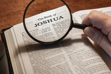 title page book of Joshua close up using magnifying glass in the bible or Torah for faith,...