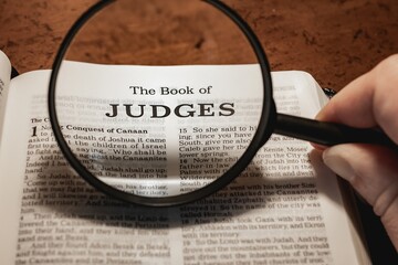 title page book of Judges close up using magnifying glass in the bible or Torah for faith,...