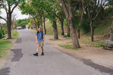 Young latin man walking along a road on the outskirts of the city surrounded by nature.