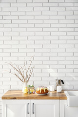 Easter cake with painted eggs, pussy willow branches and baby chickens on kitchen counter