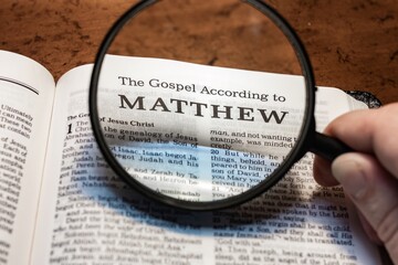 title page book of Matthew close up using magnifying glass in the bible for faith, christian, hebrew, israelite, history, religion, christianity, new testament - obrazy, fototapety, plakaty