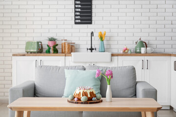 Easter cake with painted eggs and tulip flowers on table in kitchen