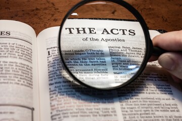 title page book of the Acts of the Apostles close up using magnifying glass in the bible for faith,...
