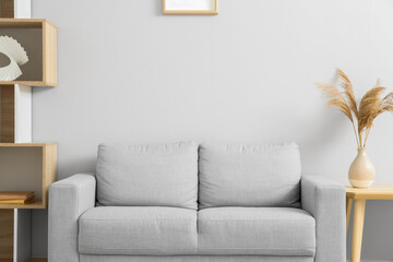 Stylish grey sofa in interior of living room