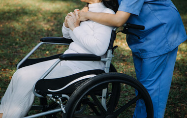 Obraz premium Asian young caregiver nurse support senior older male walking outdoors. Specialist girl doctor help and take care of elderly mature man patient doing physical therapy in public park at nursing home.