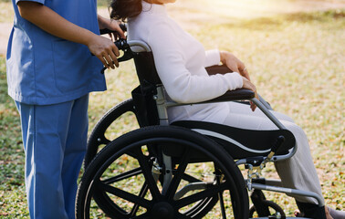 Obraz premium Asian young caregiver nurse support senior older male walking outdoors. Specialist girl doctor help and take care of elderly mature man patient doing physical therapy in public park at nursing home.