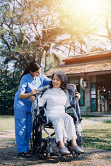 Fototapeta premium Asian young caregiver nurse support senior older male walking outdoors. Specialist girl doctor help and take care of elderly mature man patient doing physical therapy in public park at nursing home.