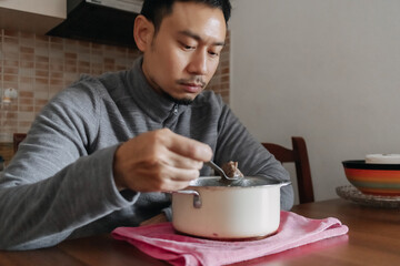 Lonely Asian man having a meal alone in his home.