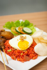 A plate of red fried rice topped with sunny side egg