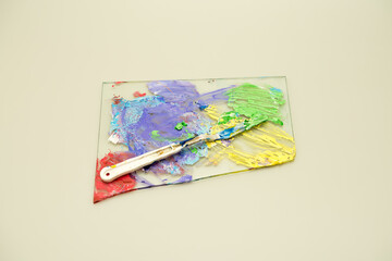 A colorful painter's palette with a plastic mixing knife isolated against a white background. 