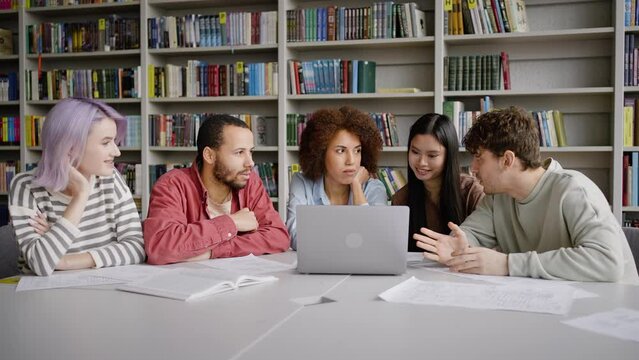 Team of students sit at desk with laptop, making researches on internet, coworking on school project