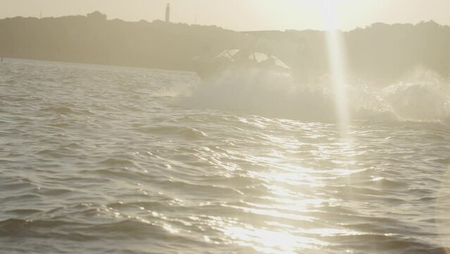 Slow motion of Wake surf boat in Lake Travis Texas with sun glare at sunset