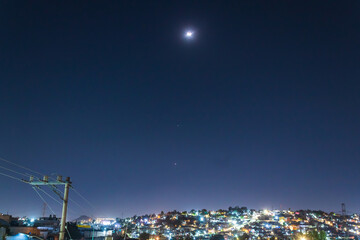 Fototapeta premium alignment of planets jupiter and venus, and the crescent moon in february 2023, planetary parade with city in the background 