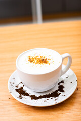 A Glass of cappucino coffee, sprinkled with coffee powder on top of the foam
