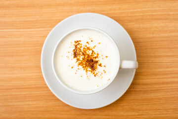A Glass of cappucino coffee, sprinkled with coffee powder on top of the foam