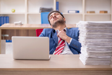 Naklejka premium Young male employee and too much work in the office
