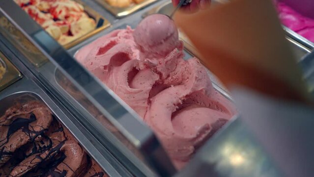 Serving pink strawberry ice cream in an Italian ice cream gelato shop