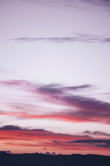 Soft pink, violet, and purple puffy clouds stretching upwards as if reaching for the heavens.