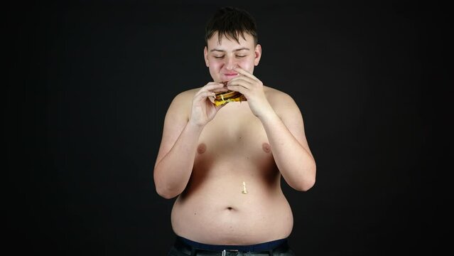 Young Overweight Man Eating Burger Naked to the Waist, Fast Food and Unhealthy Diet Concept