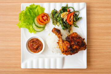 Grilled chicken thigh served with salad and a side of rice and home made chili