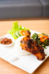 Grilled chicken thigh served with salad and a side of rice and home made chili