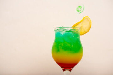 A Very colourful tropical drink served with a sliced lemon