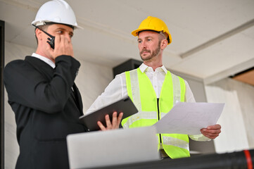 Serious Caucasian male foreman meeting with a businessman at the construction site.