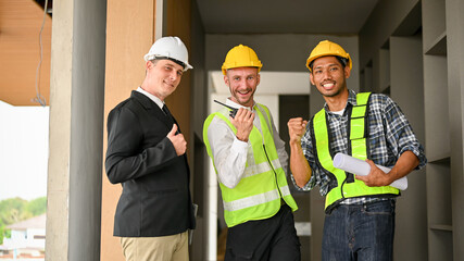 Cheerful Asian construction worker, Caucasian businessman and foreman showing fist