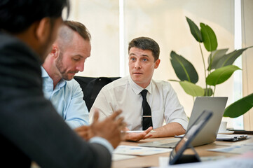Determined Caucasian male boss is in the meeting with his financial team