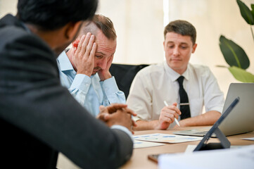 Stressed and frustrated Caucasian male CEO is in a meeting with financial consultants