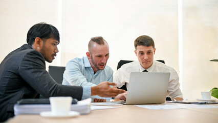Professional business financial analysts are discussing work, looking at laptop screen