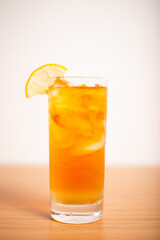 A glass of iced lemon tea served with a sliced lemon wedge