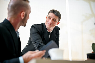 Friendly and happy Caucasian male boss looking and smiling at his worker