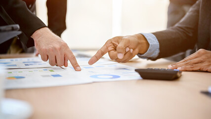 Businessmen pointing his finger on a financial report, analyzing and planning financial strategy