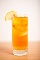 A glass of iced lemon tea served with a sliced lemon wedge