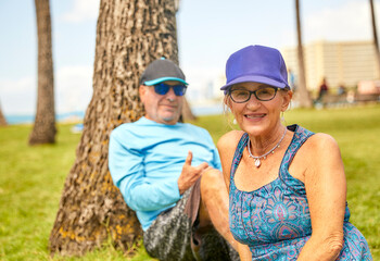 Middle Aged Senior Couple sitting on Grass in Park near the beach