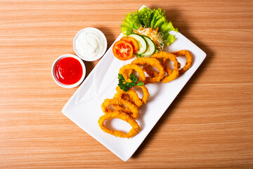 Deep fried onion rings served with tartar sauce and chili sauce