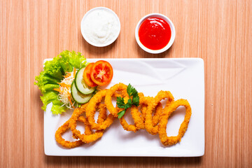 Deep fried onion rings served with tartar sauce and chili sauce