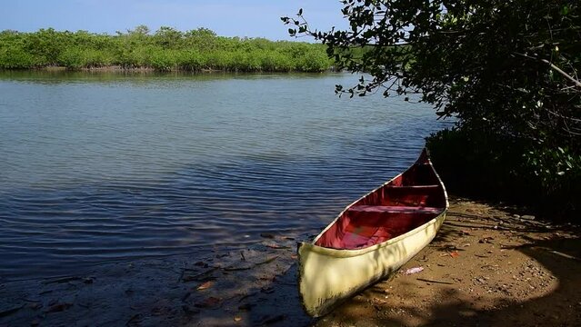 Red and white canoe laying in the sand in the mangroves of Puerto Pizarro, Tumbes Peru.