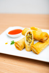 Fried spring rolls served with a side of chili sauce
