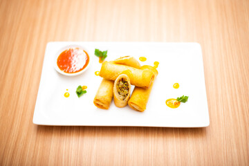 Fried spring rolls served with a side of chili sauce