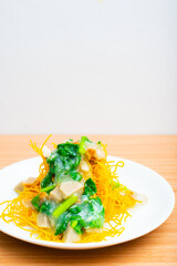 A plate of fried crispy noodles served with vegetables and sauce