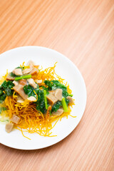 A plate of fried crispy noodles served with vegetables and sauce