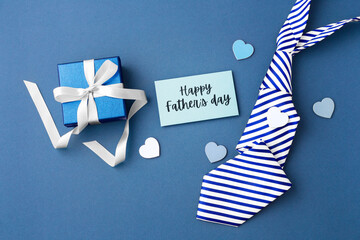 Gift box with happy fathers day card and tie on blue background