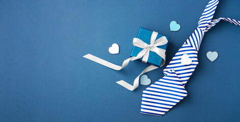 Gift box with white ribbon bow and tie on blue background, happy fathers day concept - obrazy, fototapety, plakaty