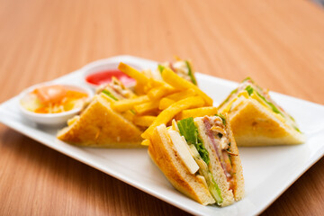 A Serving of club sandwich served with side of fries