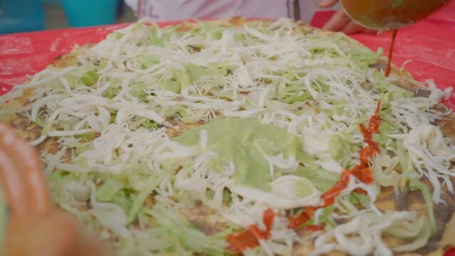Preparing traditional Food Tlayuda with traditional Oaxaca cheese Quesillo, Guacamole, salsa.