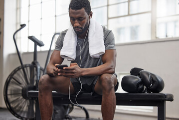 Phone, music and fitness with a black man taking a break in a gym during his boxing workout....