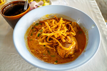 Khao Soi,Khao Soi Kai, Thai Noodles Khao Soi, Chicken Curry 
with seasoning on wooden floor, Northern Thai food concept. (Lanna food)