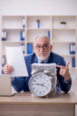 Old male employee in time management concept